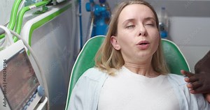 Caucasian young pregnant female in labor going to hospital with African American husband in ambulance. Woman in pain during giving child birth and man supporting. Pushes to give birth.