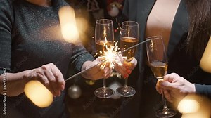 The family clinks glasses over the festive table, holds sparklers in their hands