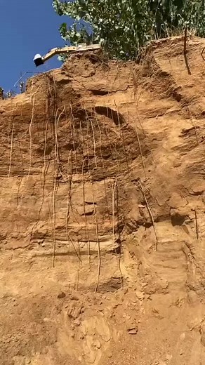 Yellow Excavator Digging on Rocky Cliff