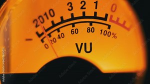 Analog dial indicator of audio signal level. Vintage arrow moves in sync with sound level. Round classic volume indicator with yellow backlight, VU meters. Close-up of old gauge measuring dB decibels