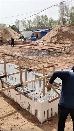 The workers are constructing and building a house foundation and reinforced concrete, wooden frames