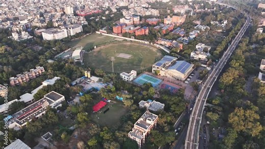 Drone shot capturing a cricket ground in South Delhi, framed by trees and neighborhoods, highlighting the city’s love for cricket set against a dense urban landscape.