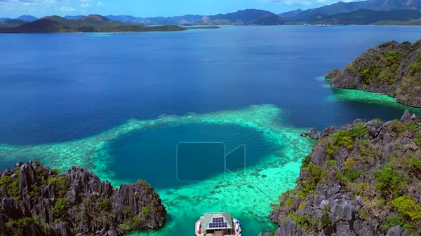 Tropical island landscape featuring jagged limestone karsts rising from deep blue and emerald green lagoons with boats and swimmers. descending panorama drone Stock Video Footage - Alamy