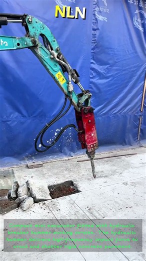 Mini‑excavator with hydraulic breaker, breaking concrete ground on construction site