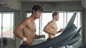 group of two muscular man running on treadmill in fitness gym at sport club . male friend workout and talking together. Shirtless sport guy Exercise on running Machine. bodybuilder cardio training