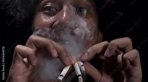 A man smoking several cigarettes at once. Maniac smoking cigarettes on a black background. Smoking addict