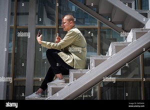 Young man sitting on the stairs and talking sign language via video link on smartphone outdoors Stock Photo - Alamy