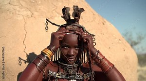 A married Himba woman puts on her traditional Erembe headpiece at her village near Kamanjab in northern Namibia, Africa.