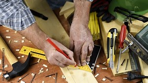 Adult carpenter craftsman takes the measure and with the carpenter's square trace the cutting line on a wooden table. Construction industry, housework do it yourself. Footage.