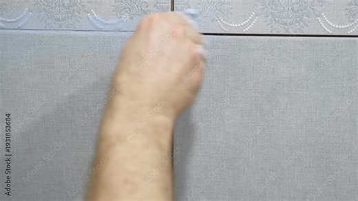 Worker using a rubber grout float to smooth grout between tiles. Carefully applying sealant to tiles joints. Workman hands smoothing caulk, using small tool to remove excess and create clean seam.