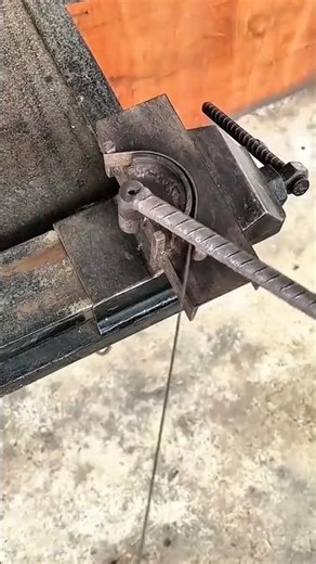 bending a long dark metal rod manually using a sharp metal machine on a professional project area