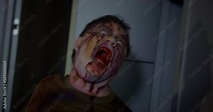 Hungry zombie with a bloody mouth and face goes to attack his victim, waving his hands, and the camera shakes making the atmosphere even more creepy, front view