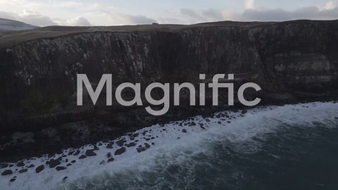 Majestic Kilt Rock Waterfall in Scotland with snow patches, serene landscape under cloudy skies | Premium Stock Video Footage