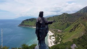 Popular tourism landmark of Cristo Rei Jesus Christ, aerial drone slowly moving towards statue with beautiful landscape backdrop in capital Dili, Timor Leste