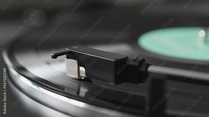 A vinyl record spinning on a turntable platter. Listening analog music on the semi-automatic gramophone. Record player needle touching the vinyl.