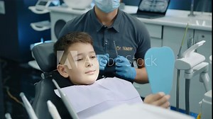 Calm boy sitting in dentist chair opening mouth wide while dental expert in latex gloves and medical mask checking teeth with tooth scraper, concave mirror. High quality 4k footage Stock Video