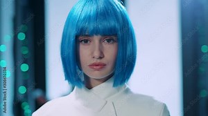 Future female robot with blue hair looking at camera on technological background. Portrait attractive robotic woman IT specialist working in advanced database of cyberspace.