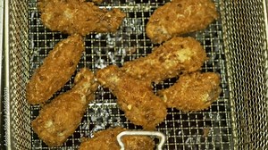 Deep fryer with boiling oil and chicken. Large, deep fryer container for frying food Buffalo wings. Restaurant deep fryer chicken wing deep fried on hot oil. Chicken wings in breading.