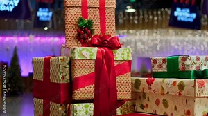 Stacked gift boxes wrapped in holiday-themed paper and ribbons, with Black Friday signs hanging nearby and shimmering decorations in the background.