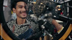 Happy Asian repairman smiling complacent while wearing chain of bike successful. Young man fixing and maintenance bike wheel in bicycle shop. Maintenance and repair Concept