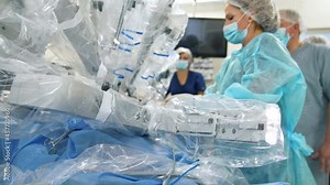 Surgical robot. Female surgeon with modern medical equipment in the operating room. Medical specialist works with robotic device during surgery. Close-up.