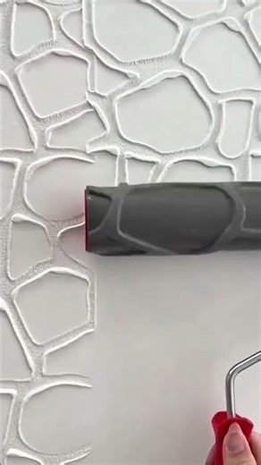 Applying decorative wall texture patterns using specialized paint roller for artistic interior finis