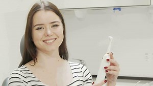 Download Beautiful woman examining electric toothbrush for free