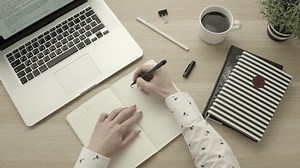 Female hands write to do list on blank notepad. Setting goals concept. Top view desktop. Productivity and success. Office workspace flatlay