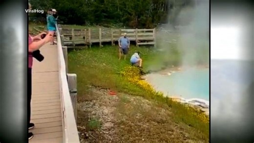 Tourist touches hot spring with hand at Yellowstone
