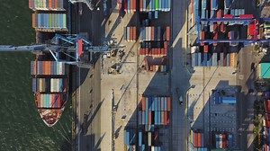 Download Cargo containers being unloaded by a gantry crane from a container ship