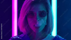 Portrait of a young stylish woman in sunglasses smoking a hookah and blowing out puffs of smoke. Close up. Slow motion.