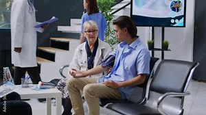 Senior doctor measuring blood pressure, taking patient pulse and hypertension, in hospital lobby reception. Handheld shot. Monitoring asian young man health vitals