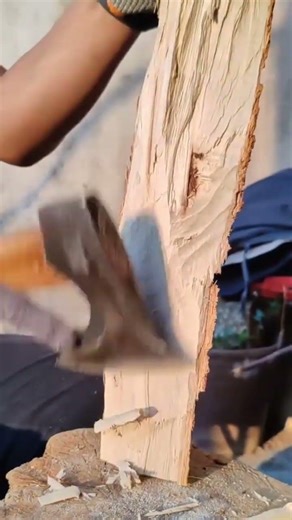 smoothing wide wooden board surface using a sharp axe