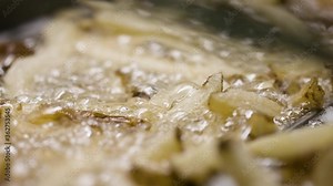 Deep frying a basket of fresh-cut french fries. Professional kitchen deep fryer. Shot in 4k