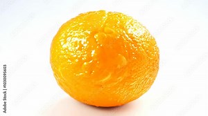 Rotating orange with bright citrus skin, dimpled texture, on a white seamless background, filmed with high key lighting