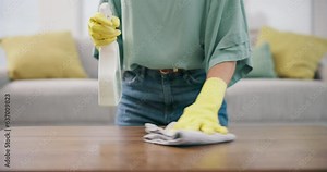 Housekeeping, closeup and woman cleaning the table with detergent, cloth and gloves in living room. Zoom of female maid, cleaner or housewife wipe furniture for dirt, dust or bacteria in an apartment
