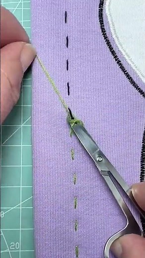 Cutting purple fabric thread precisely using a sharp metal sewing scissor tool for neat and perfect