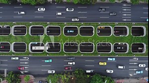 Grade separation in front of in-city interchange, underground lanes seen through openings in green divider of large street, top-down aerial shot. Huangpu W Avenue at Guangzhou. Light car traffic