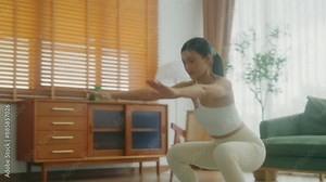 Young Asian beautiful woman doing aerobic exercise at home. Attractive girl doing workout by squatting, follow instructions video from online trainer for health in house