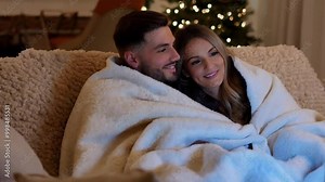 Couple Snuggled in Blankets Watching Christmas Movies A couple enjoying a Christmas movie marathon on the couch.