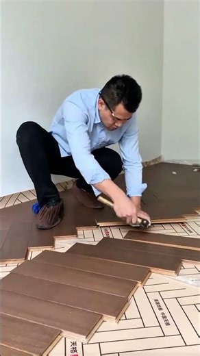 installing wooden parquet flooring in a room by hitting gently to make the joints neat and tidy