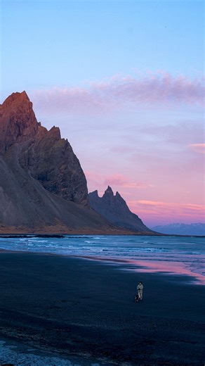 【冰島暖冬日記 Final Ep.】 2025 年，是我在冰島度過的第 9 個冬天。 - 📍Vestrahorn（西角山） & Brunnhorn（蝙蝠山） - 從那個安靜得不真實的東部峽灣啟程回家， 699 公里的歸路， 像是一條慢慢把人送回日常的走廊。 - 原本以為，這只是一段單純的趕路， 畢竟這條一號公路， 早就成了這些年生活裡最熟悉的風景。 直到車子駛近Vestrahorn的那一刻， 冰島又一次，在最後關頭留了個小小的驚喜。 - 天空忽然被染成一整片溫柔的粉金色， 在25年這個天氣反常的12 月， 沒有厚重白雪覆蓋的黑沙灘， 卻被夕陽鍍上了一層暖暖的光。 潮水退去後留下的水窪， 像灑滿地面的碎鏡子， 把那座一向冷峻的山，映得格外柔軟。 - 停好車， 帶著烏龍在黑沙灘上漫步， 看著光線一點一點收進雲層裡。 那幾分鐘，車裡沒有放音樂， 只有海浪拍打黑沙的聲音， 和遠處風輕輕繞過山形的回音。 - 這大概是這些年裡， 我看過最溫柔的一次 Vestrahorn。 以前來，遇過被大霧整座吞沒的山形， 也撞見過被大雨敲得灰濛濛的一整片天， 有時只是陰鬱得讓人想快點上車取暖。 但那一天，山好