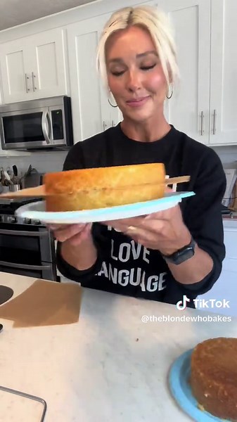 This is my process after baking my cakes. -Let cake cool IN cake pan for 15-30 minutes. -Trim off rounded top (if any) -Set cake board on top of cake in cake pan, flip over and remove pan. -Use cake leveler to cut in half -Place parchment paper between the layers to avoid cake sticking. -Put cake in freezer for 3-5 hours. -Enjoy the cake trimmings. (Thank me later 😉) (Volume Up 🔈) 🤍 My sweatshirt is from @Live Love Gameday® #Theblondewhobakes #theblondewhobakescakes #cake #cakes #cakedecorati