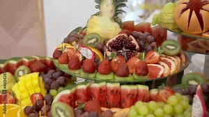 Festive buffet with exotic fruits. Fresh ripe sliced fruit grapes, watermelon, strawberry, kiwi, orange, mango, grapefruit, pineapple, coconut, pomegranate, pear, pitahaya. Healthy Eating.