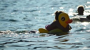Summer Vacation Woman floats on an inflatable yellow duck, a water toy swim ring. Positive happy woman relaxing and enjoying family summer travel holidays vacation on the sea. Slow motion