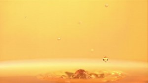 The super slow motion drop falls into the apple juice with splashes. On a yellow background. Filmed on a high-speed camera at 1000 fps. High quality FullHD footage