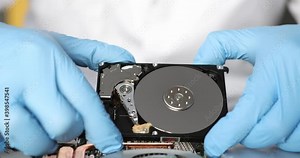 4k video of man repairing detail of computer. Technician male fixing mainboard of device. Blue protective gloves on person. Metal disc. Technology and diy concept