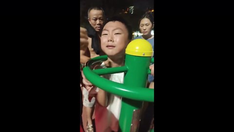 Boy stuck inside playground equipment is helped out by onlookers