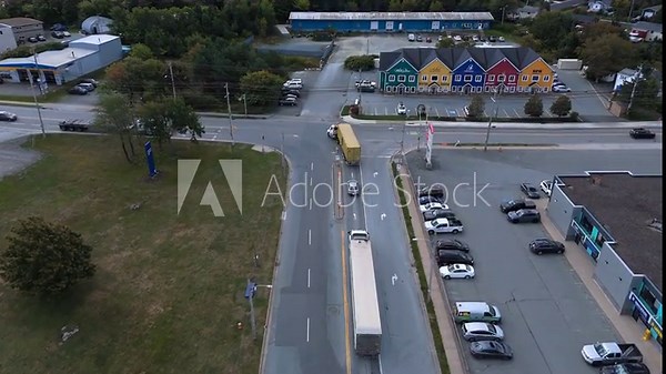 High drone aerial shot: large logistics warehouse complex in Halifax with dozens of semi-trucks and trailers at loading docks. Active freight terminal in Nova Scotia, Canada on a bright day 4K.