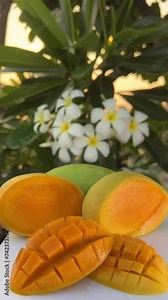 Close-up of the fresh mango juice poured in a tall glass next to a mango cut into cubes on a sunny day. High quality 4k footage